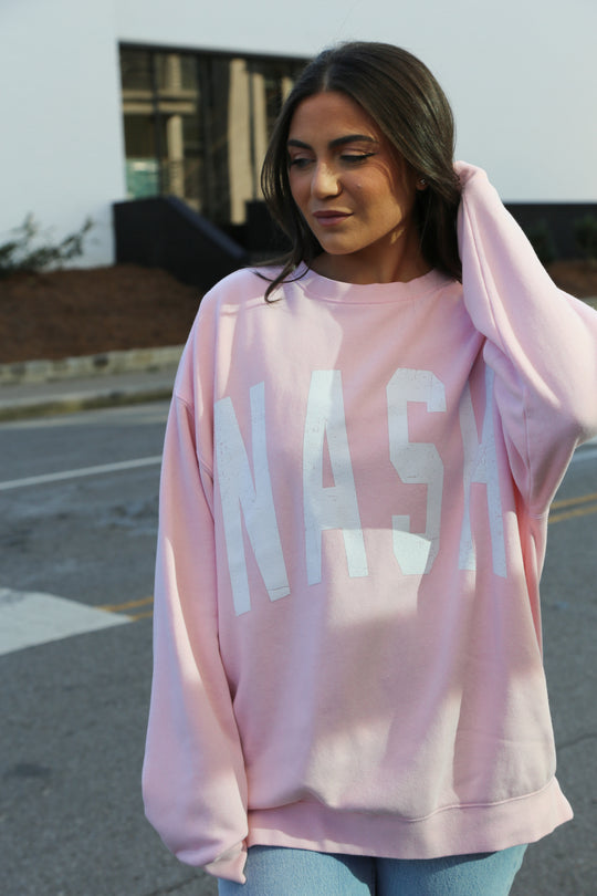 Light pink oversize crewneck with nash screen printed across the front 