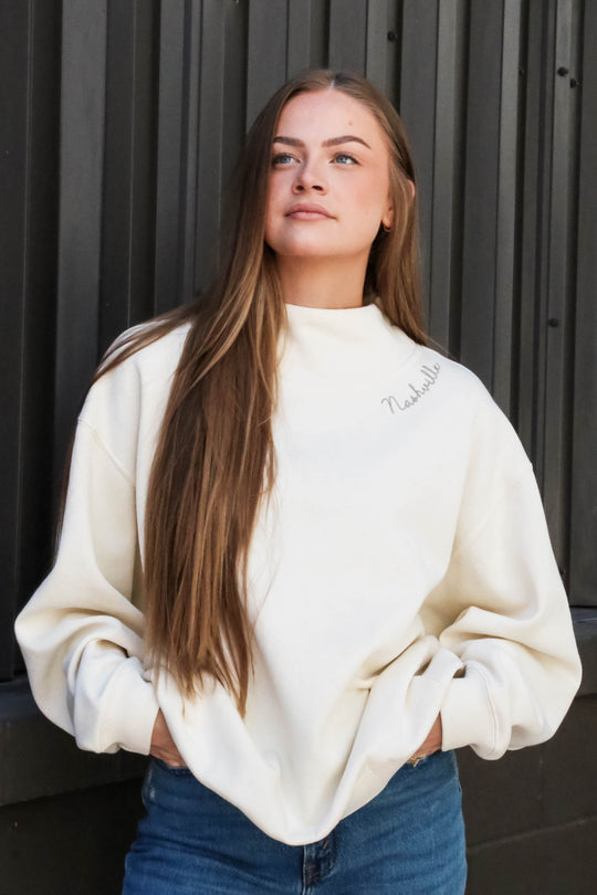Front view of the cream turtleneck with Nashville script embroidery along collar 