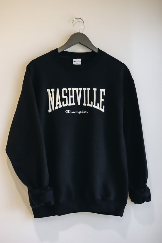 Hanging photo of the black powerblend crewneck with cream Nashville 3D embroidery across the chest