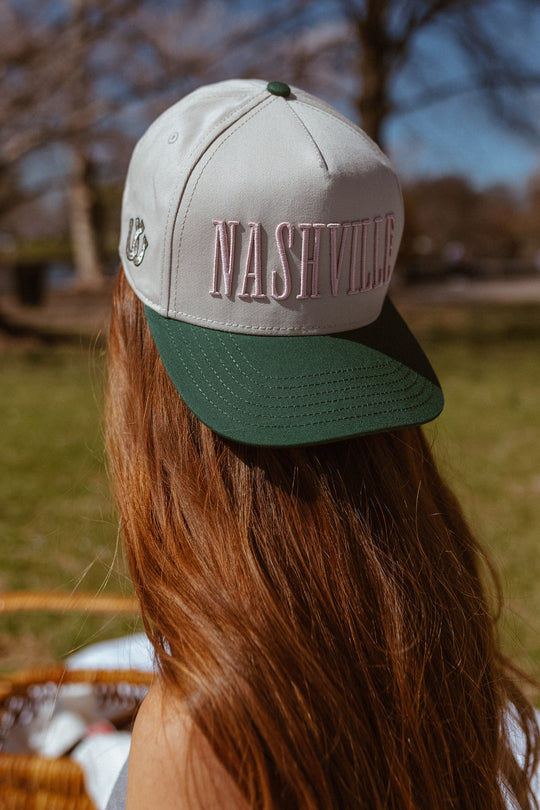 Model wearing the green/cream snapback  with embroidered Nashville in pink backwards