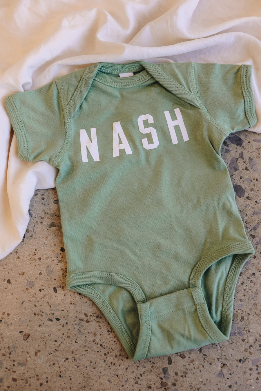 Light green baby onesie with NASH on the front.