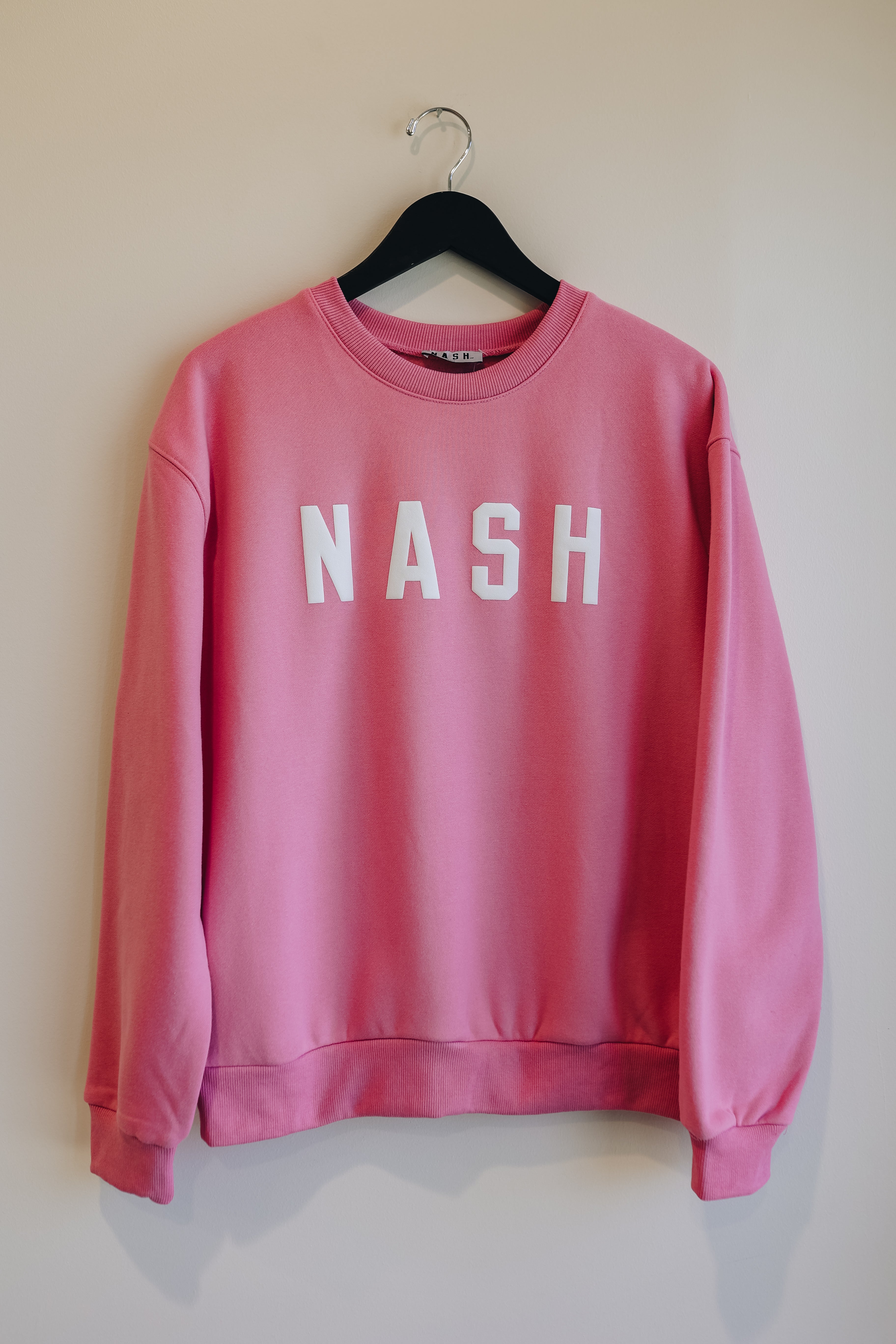 Front view of the hot pink crewneck, with NASH in a puff ink on the front