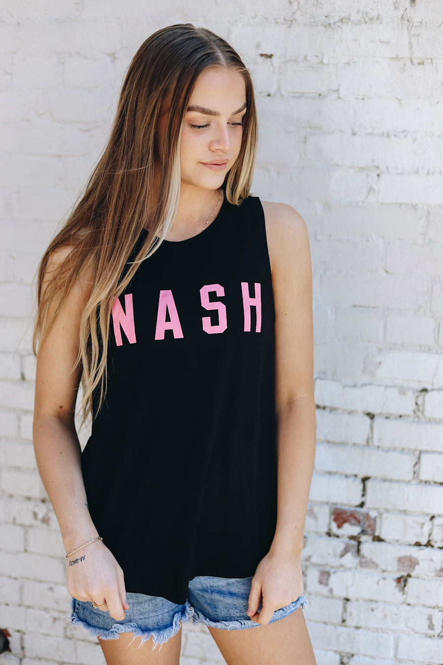 Casen modeling the black racerback tank with pink NASH printed on the front